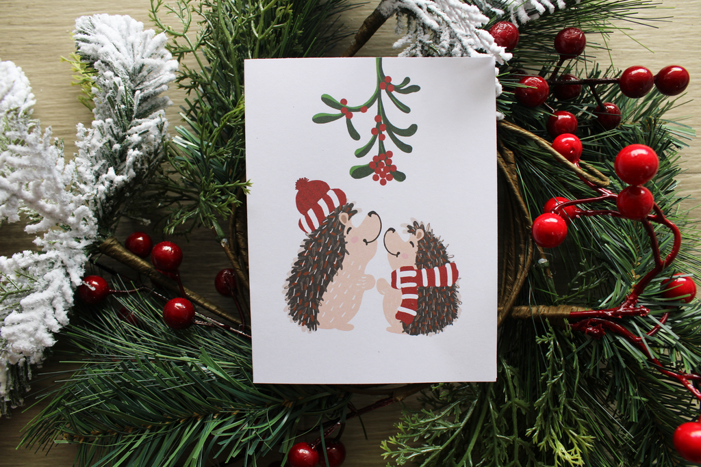 Christmas card with hedgehogs and mistletoe on a wreath background