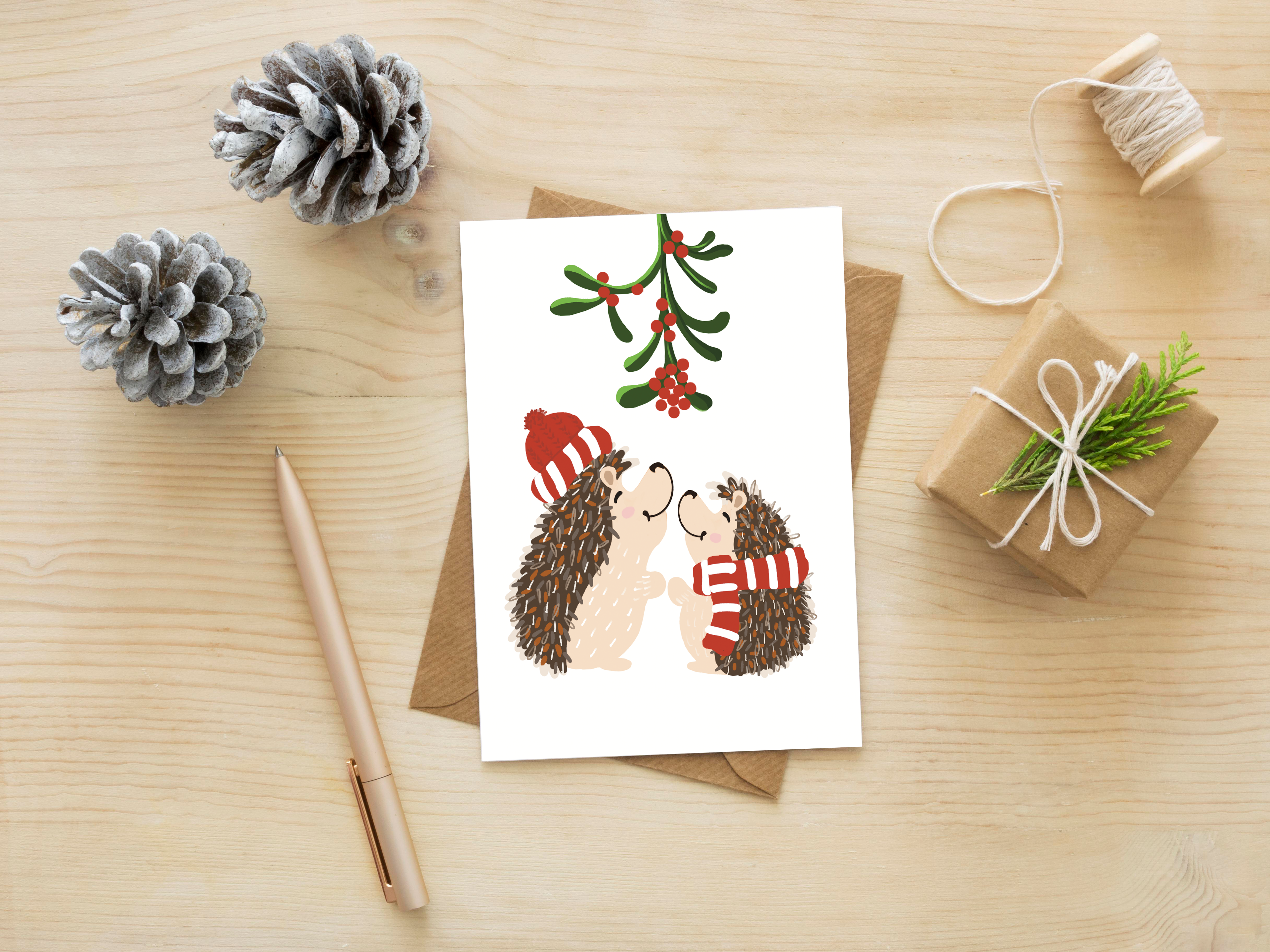 Christmas card with hedgehogs on a wooden surface with decorative items