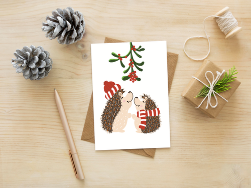 Christmas card with hedgehogs on a wooden surface with decorative items