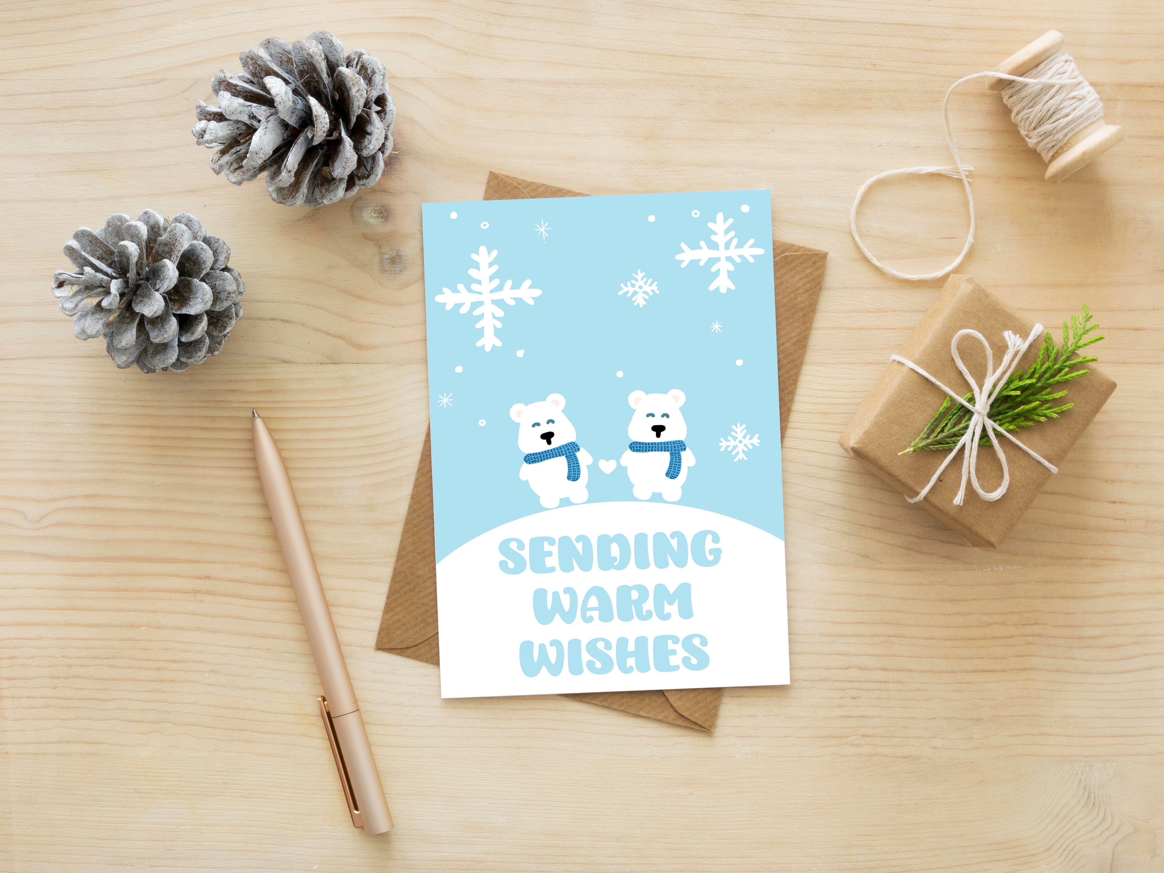 Greeting card with polar bears and snowflakes on a wooden surface with decorative items.